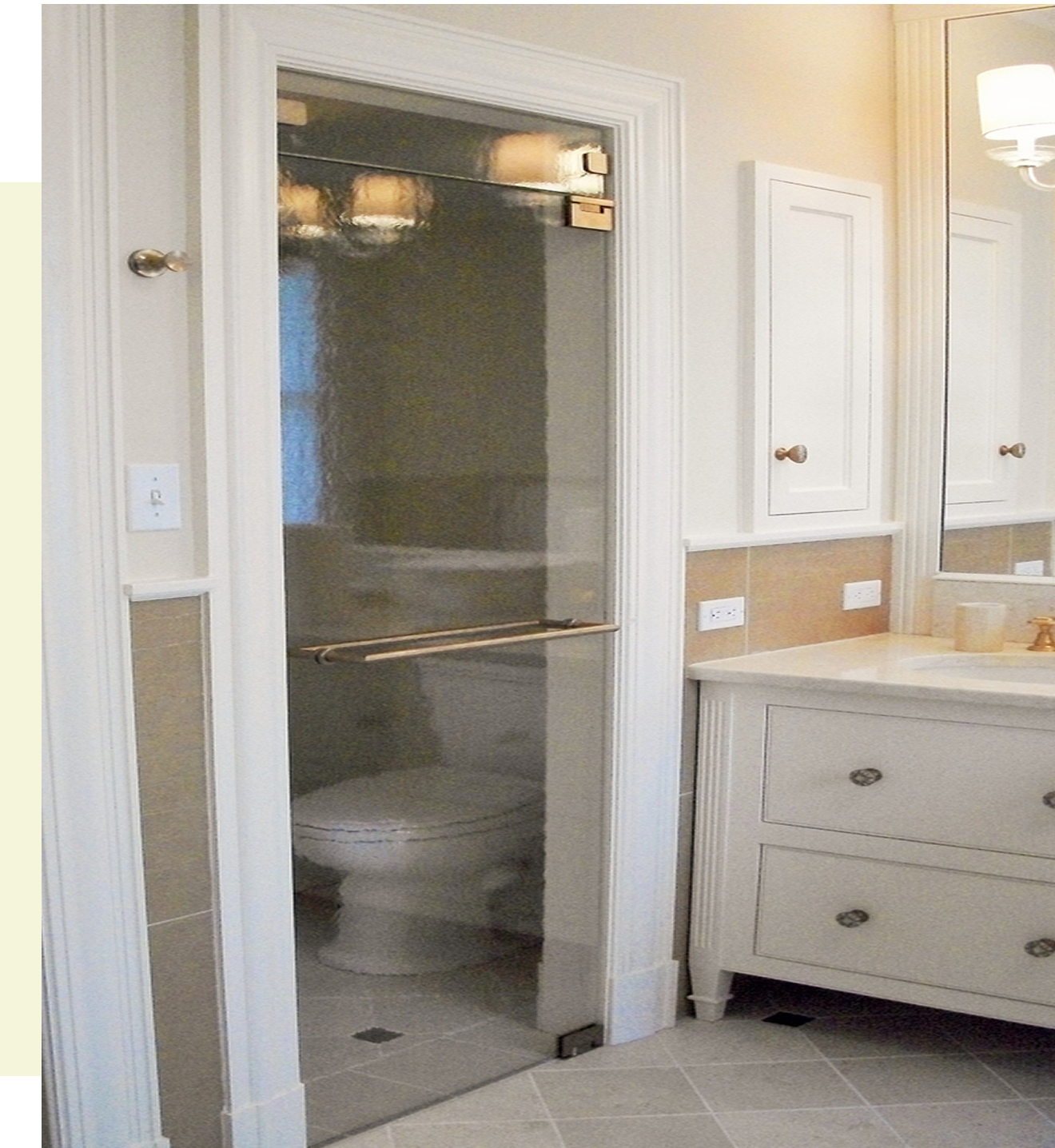 Bathroom with toilet behind glass door.