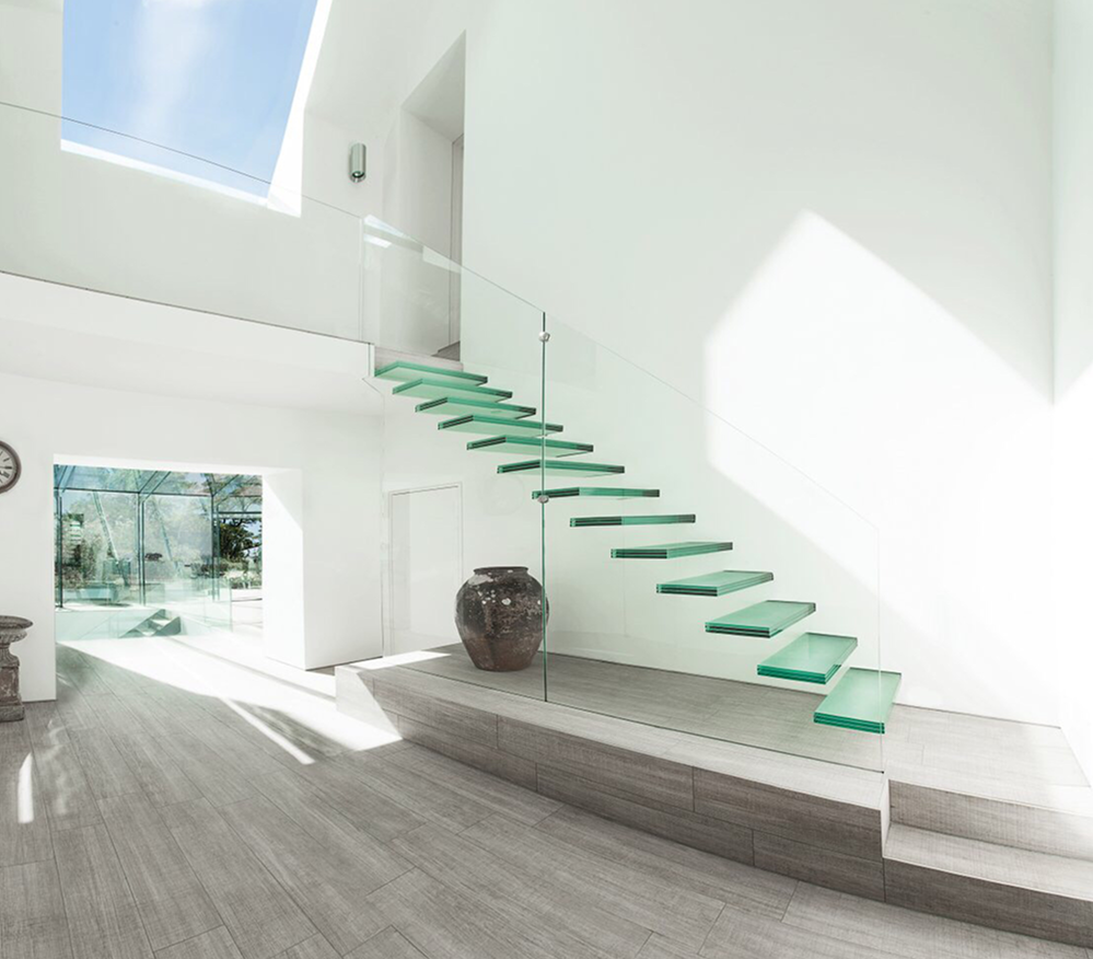 Modern interior with floating glass staircase.